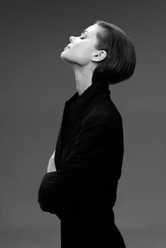 Black and white profile of a woman with elegant hairstyle wearing dark clothing.