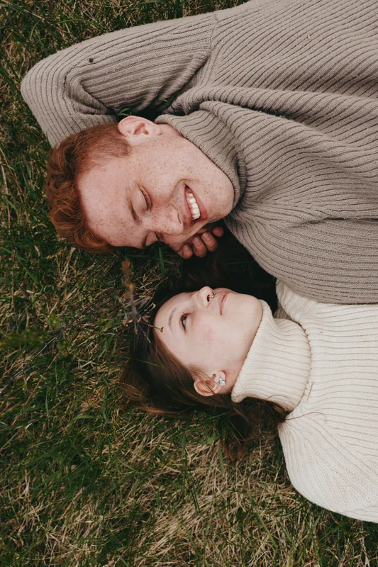 Couple lifestyle outdoor affection sweater grass smiling relaxed candid cozy moment warmth connection leisure weather gentle hug tenderness portrait serenity nature scenery romance happiness together