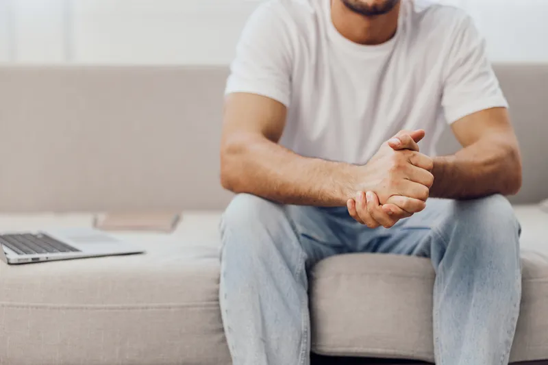 Casual man sitting on a sofa, reflecting in a comfortable home environment. Perfect for modern lifestyle and wellness themes, showcasing relaxation and tranquility.
