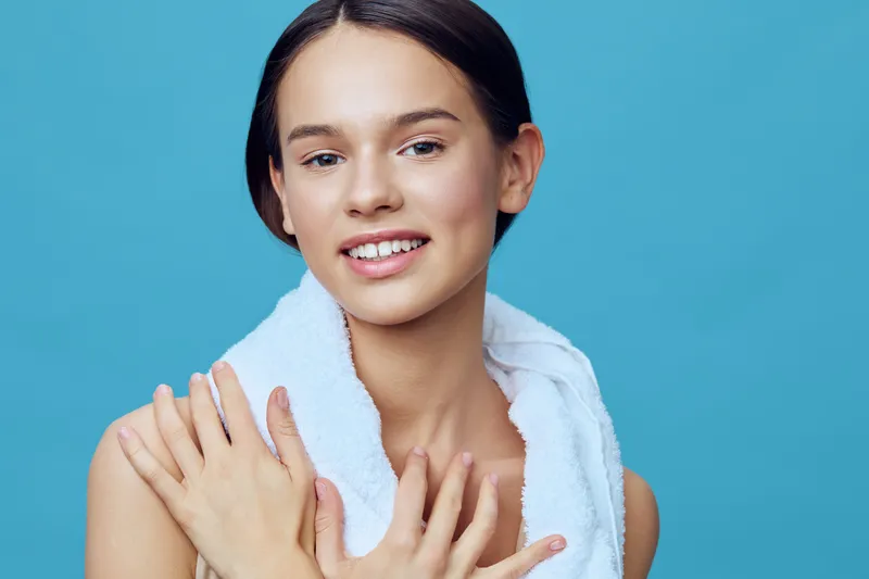 Young model with healthy skin showcasing natural beauty against a turquoise background, evoking confidence and youthfulness, promoting skincare and wellness concepts