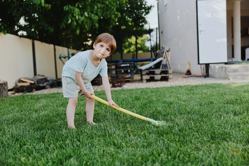 Happy boy playing in the garden, enjoying outdoor activities, surrounded by green grass and sunlight, showcasing the joy of childhood and exploration.