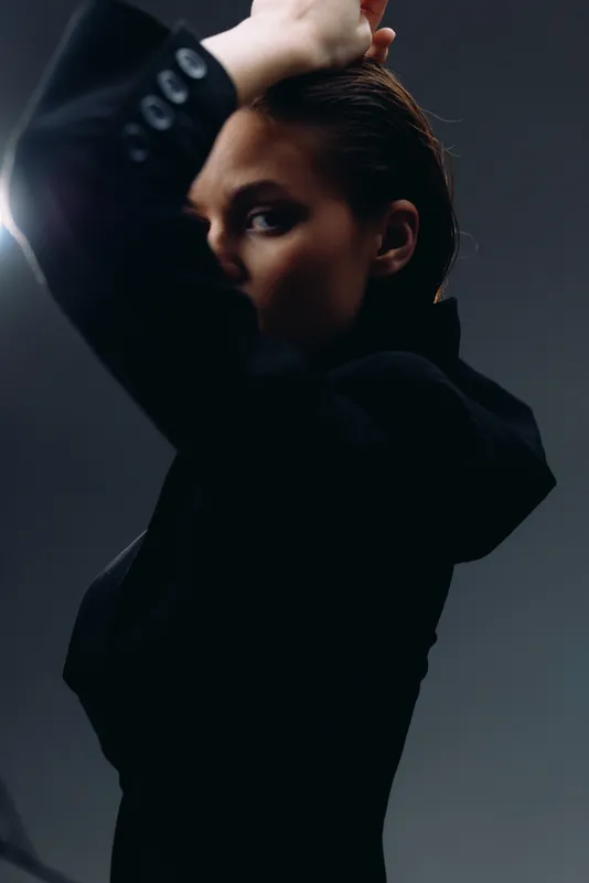 Mysterious woman in black clothing with dramatic lighting and shadow in studio setting