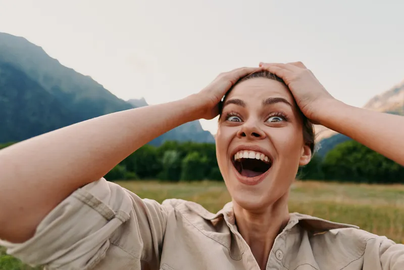 Woman outdoors portrait captures happiness and smiling lifestyle in a scenic field under natural daylight, conveying carefree joy and relaxed energy. Bright smile highlights energy and optimism.