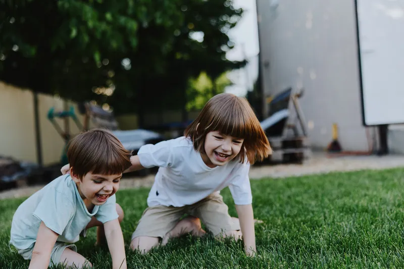 Happy children playing outdoors on a sunny day, enjoying their time in the garden with lush green grass and bright smiles. Perfect for family moments.