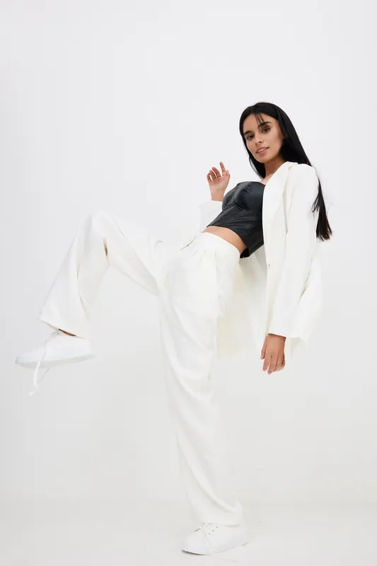 stylish woman in white pants and jacket striking dynamic pose with confident expression on plain white background, modern casual fashion and empowered mood
