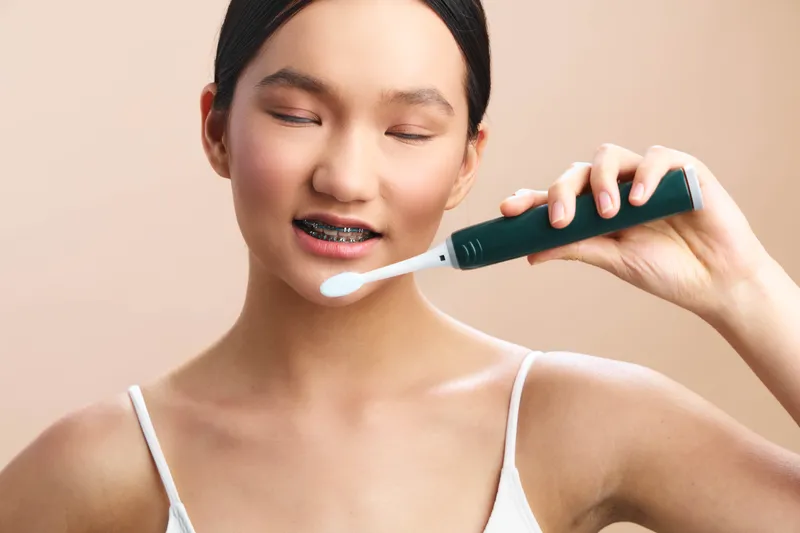 asian woman with braces brushes teeth in a bright bathroom, emphasizing dental care and personal hygiene, a clean healthy lifestyle moment captured in soft lighting.