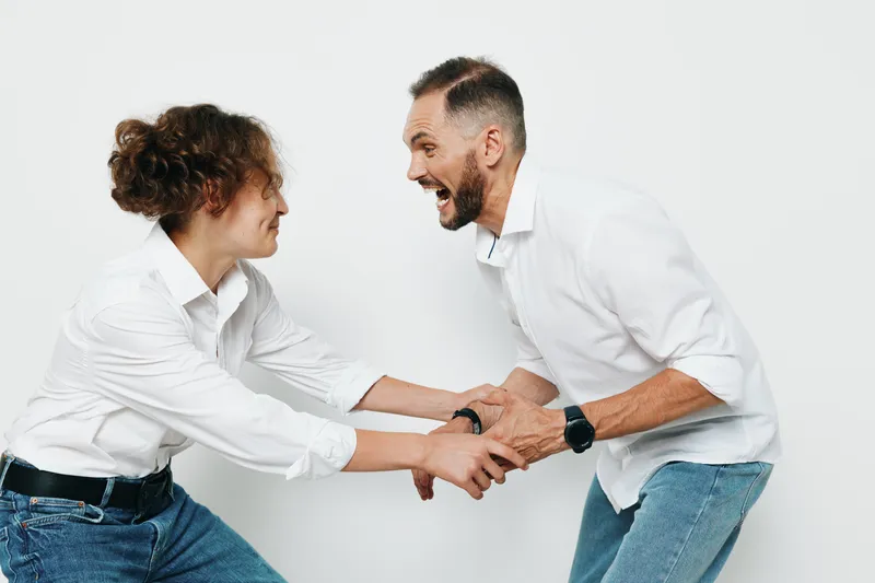 A professional business man and colleague share a dynamic moment against a clean colored background, expressing energy, teamwork, and motivation in a vivid workplace scene.