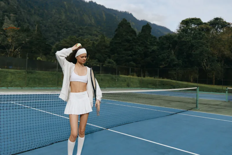 Athletic young model in stylish tennis outfit on blue court, showcasing confidence and vitality, perfect for healthy lifestyle concepts