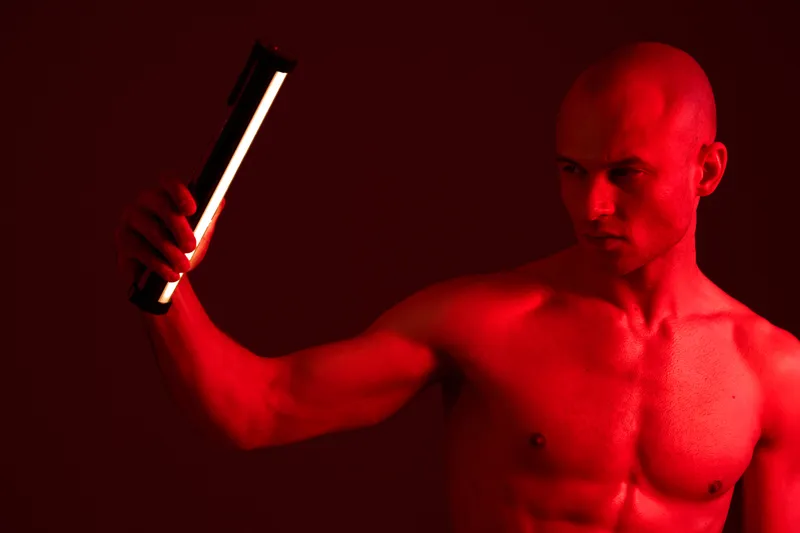 Striking black and white image of a focused man holding a flashlight, creating dramatic lighting effects, emphasizing strength and intensity in a captivating composition.