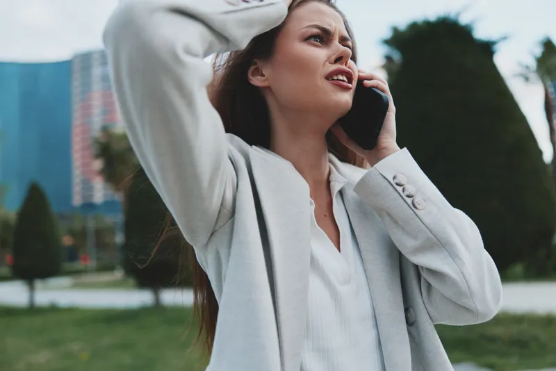 Confident businesswoman in a light gray blazer on the phone, expressing determination amidst a modern urban backdrop, perfect for corporate themes.