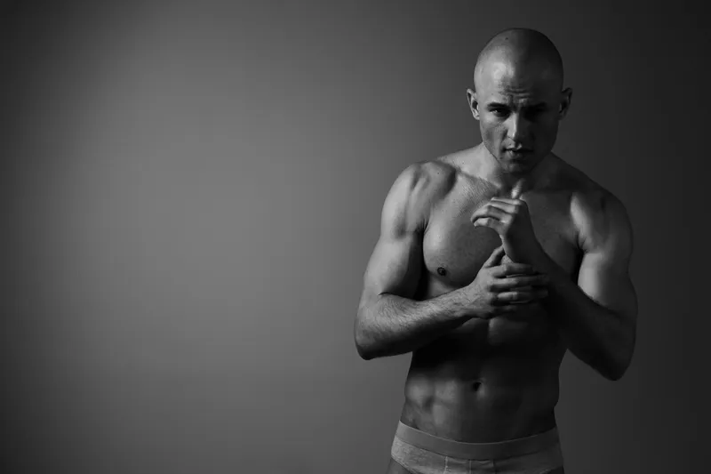 Determined man in a black and white image, showcasing strength and focus with a powerful stance, perfect for fitness and motivation themes.