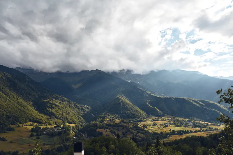 Mountains and valley scene with lush greenery under a cloudy sky, a wide panorama showcasing tranquil nature and rugged hillside, perfect for travel inspiration and outdoor photography