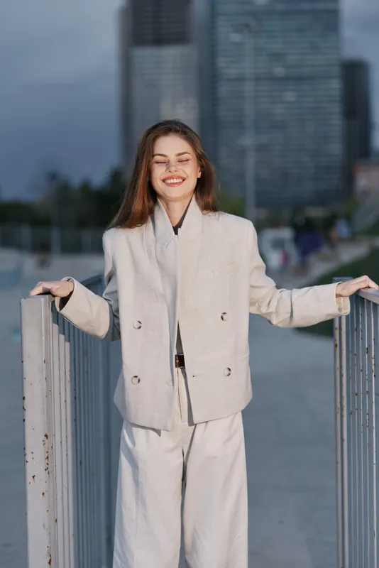 Happy young woman in beige suit smiling outdoors urban background autumn fashion style confident woman portrait