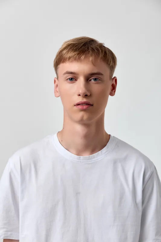 Young man, casual fashion in a white tshirt, studio shot with a clean background, minimal lifestyle image suitable for fashion, advertising, branding and ecommerce use