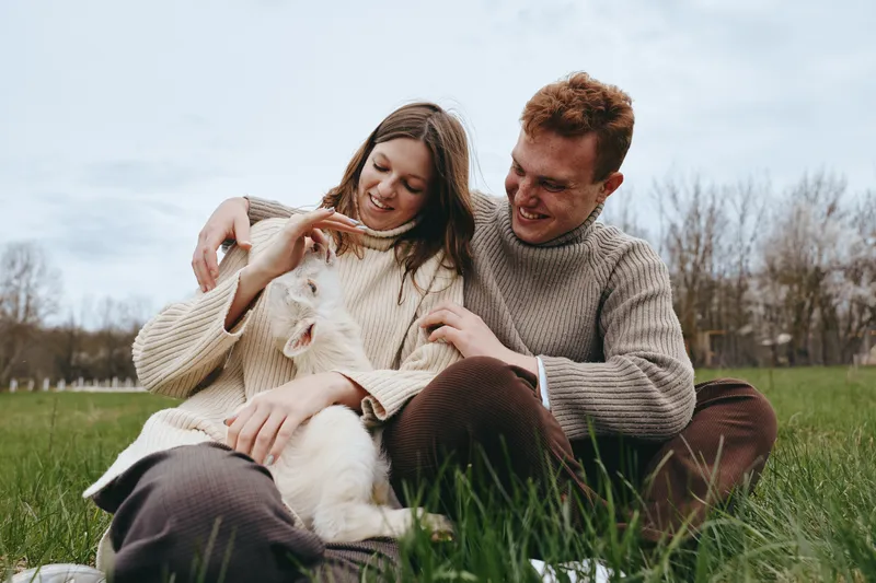 Couple outdoors affection cozy sweaters grass park together natural moment sunlight breeze candid portrait relaxed scene
