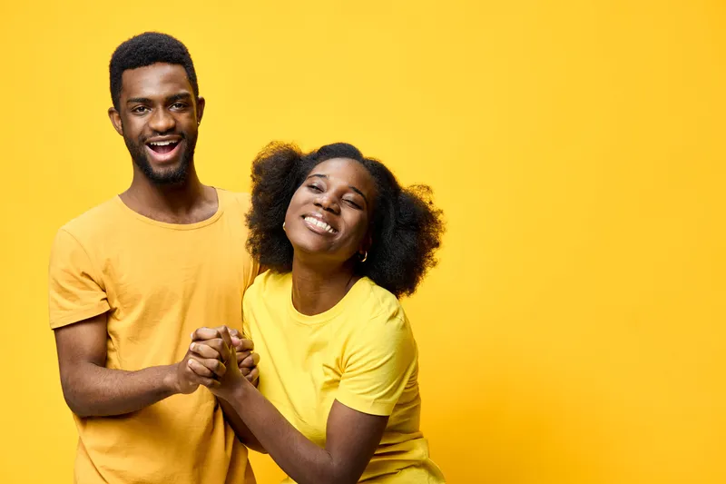 Happy couple celebrating together on a bright yellow background, showcasing joy and affection in matching outfits, perfect for seasonal marketing and lifestyle themes