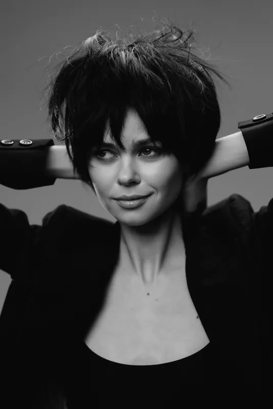 Black and white portrait of a woman with short hair and confident expression in studio lighting.
