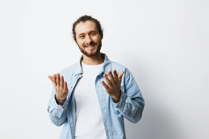 Smiling young man in a denim jacket, expressing joy against a white background, ideal for concepts like happiness and self expression