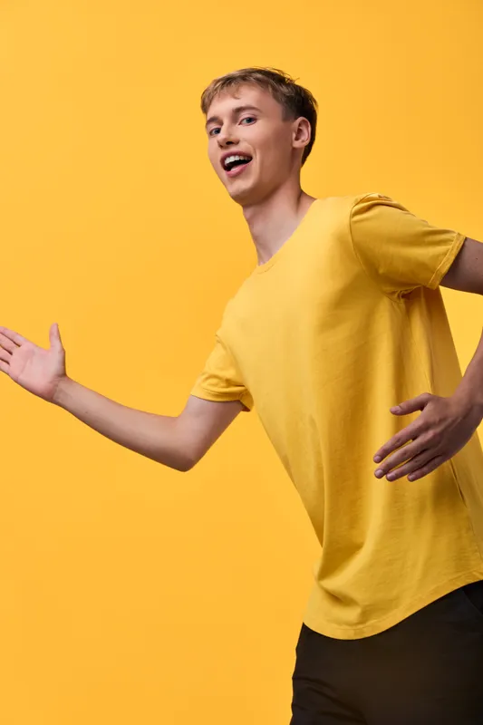 Energetic youth in a bright yellow tee radiates joy and motion, capturing playful movement and a vibrant lifestyle moment for fashion, lifestyle or creative stock photography.