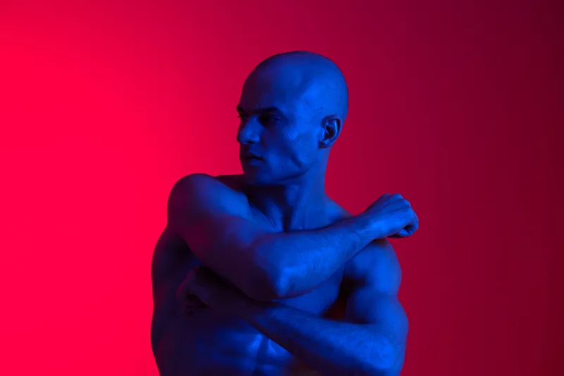 A striking black and white image of a man posing confidently against a vibrant background, showcasing strength and determination through body language.
