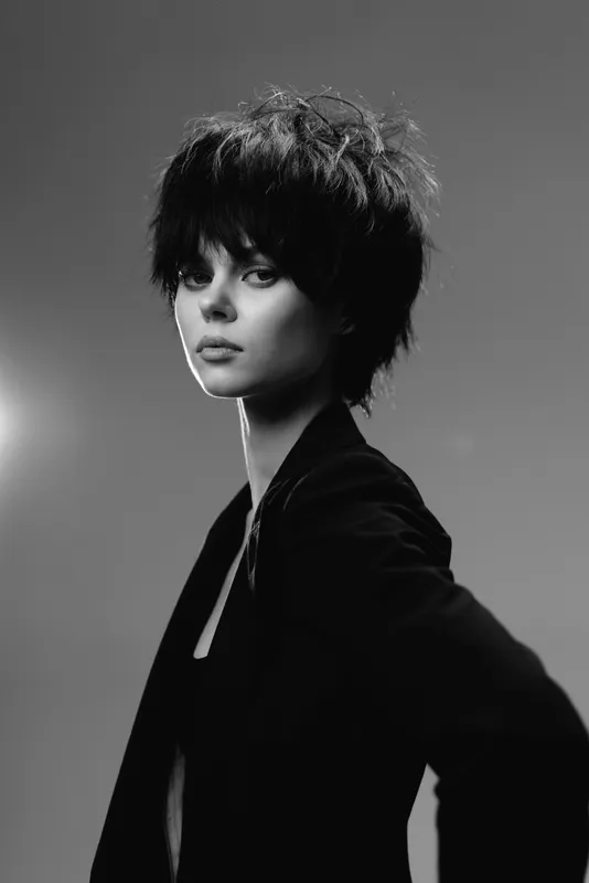 Black and white portrait of a young woman with short hair wearing a dark jacket, displaying a serious and confident expression.