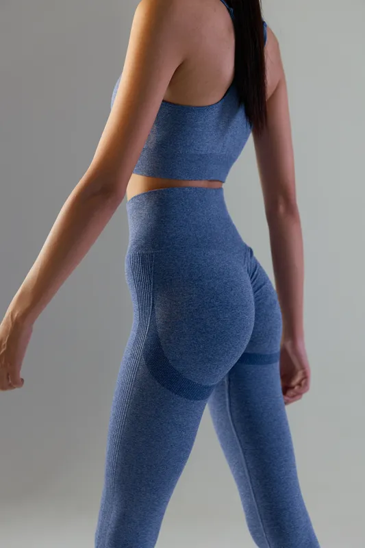 Woman sport fitness wearing seamless blue workout outfit, showing toned body and smooth fabric texture in modern studio lighting, active lifestyle concept.