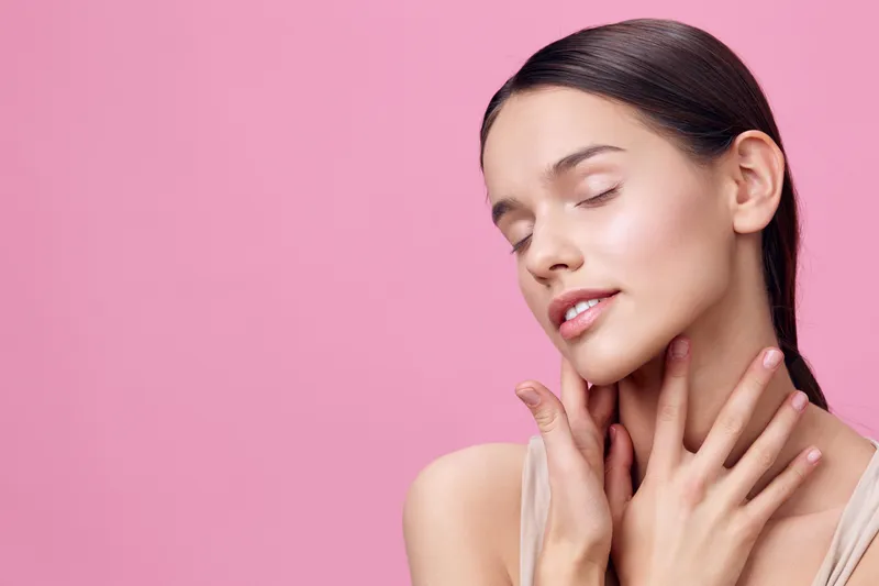 Young woman with closed eyes against pink background, showcasing natural beauty and skincare Soft expression highlighting tranquility and confidence