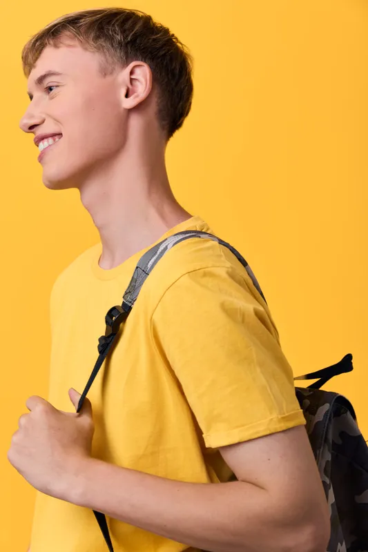 Backpack, youth, student, travel, casual, yellow shirt, strap, outdoor, fashion, smile, energy and exploration in a bright everyday moment, capturing youthful confidence and style