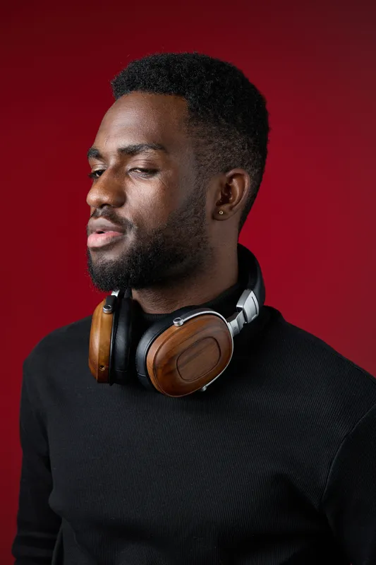 Portrait of a stylish Black man wearing headphones, showcasing a confident expression against a vibrant red background, perfect for music or technology themed concepts