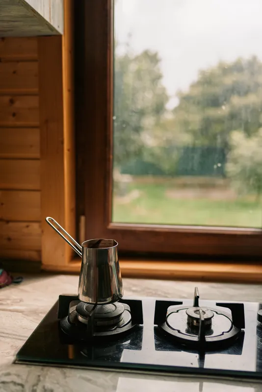 Cozy kitchen scene with a pot on a gas burner, sleek stove, and a bright window overlooking a green garden, inviting warm home cooking moments