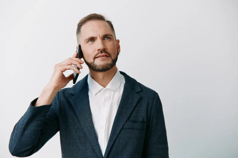 A professional man on a call, business mood, calm and confident, with a focused expression against a solid colored background, isolated and clean.