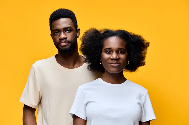 Happy young African American couple against a vibrant yellow background, representing love, togetherness, and joy in casual attire