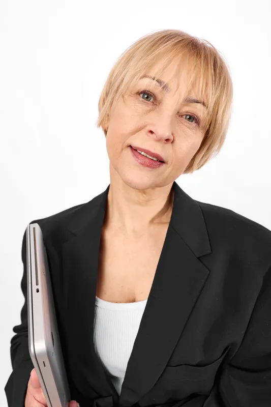 Woman in business suit smiles in portrait, holding smartphone, professional corporate headshot on white background, showing technology communication with mobile device.