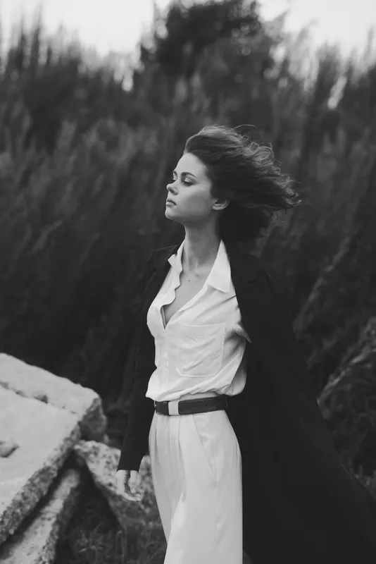 Fashion, woman, wind, outdoor, elegant, coat, dress, monochrome, breeze, dramatic pose, flowing hair, confident stance for runway inspired edginess and cinematic mood