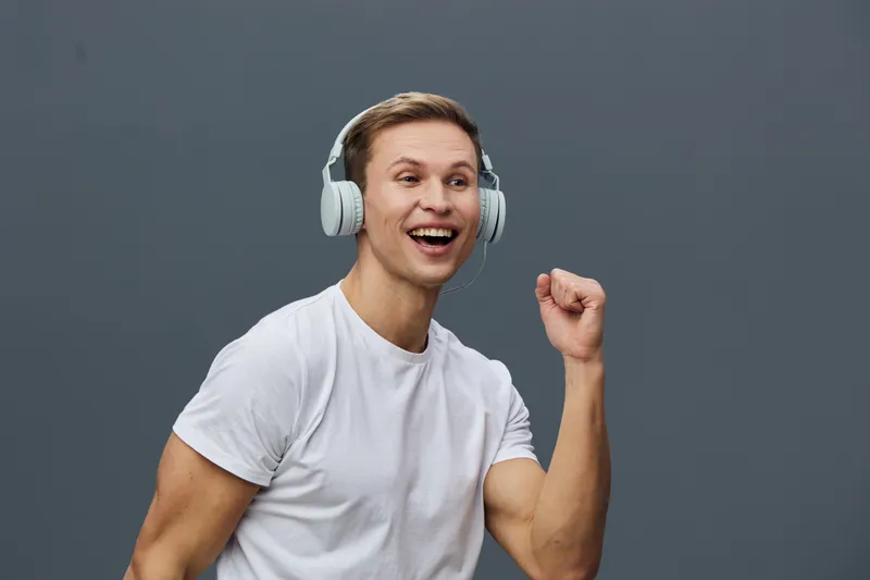 Happy young man wearing white headphones enjoy music listen dancing isolated on gray background digital detox concept