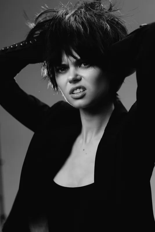 Black and white portrait of an expressive woman with messy hair and intense emotion in studio lighting