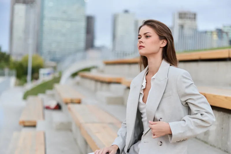 professional business woman in light gray suit sitting outdoor city urban environment thoughtful confident young Caucasian female