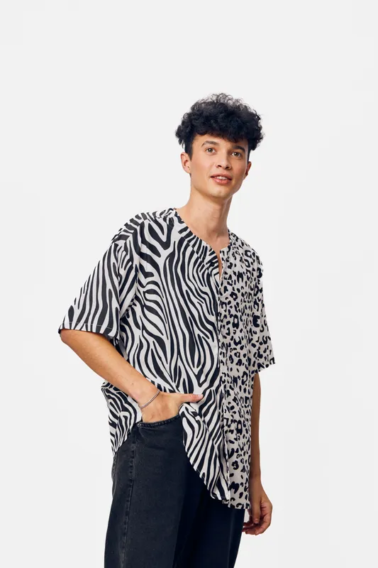 young man wearing a black and white zebra and leopard print shirt smiling confidently with curly hair on a light background, casual fashion style, modern look