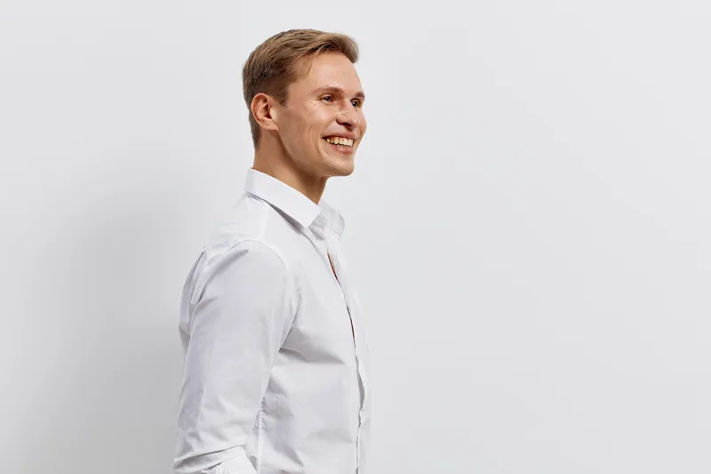 Smiling young caucasian man wearing white shirt side profile look away isolated on plain background digital nomad concept