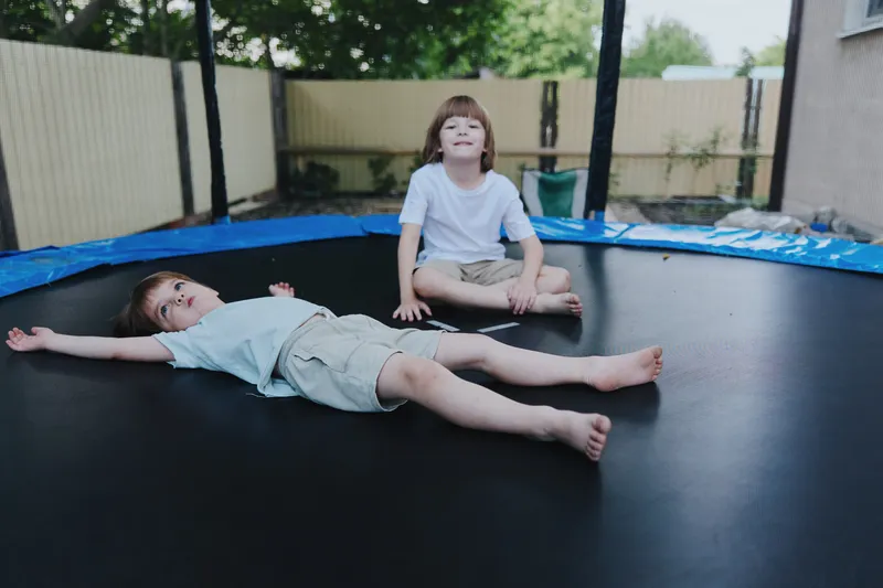 Active children enjoying fun time on a trampoline, expressing joy and playfulness in a sunny backyard setting, perfect for capturing happy childhood moments. ###