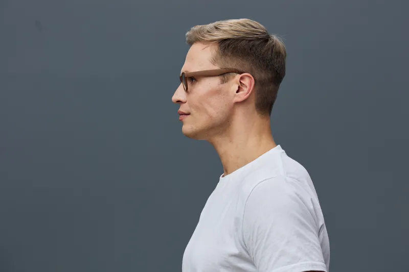 Profile view thoughtful young man wear glasses white t-shirt isolated grey background digital nomad concept technology lifestyle portrait