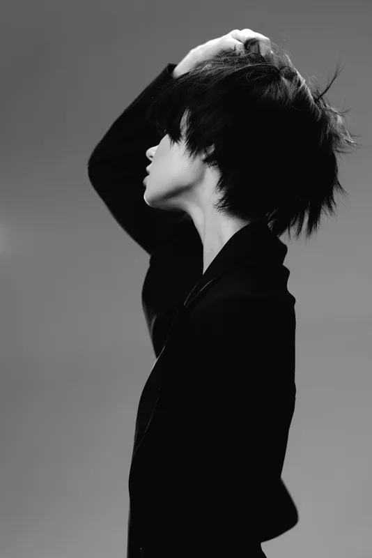 Black and white portrait of a woman with short hair touching her head in a thoughtful pose.