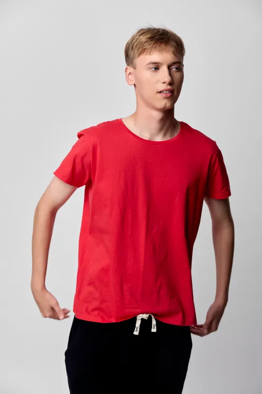 Red t shirt on a young man in a casual studio setting, relaxed pose, lifestyle fashion and everyday wear concept for versatile clothing