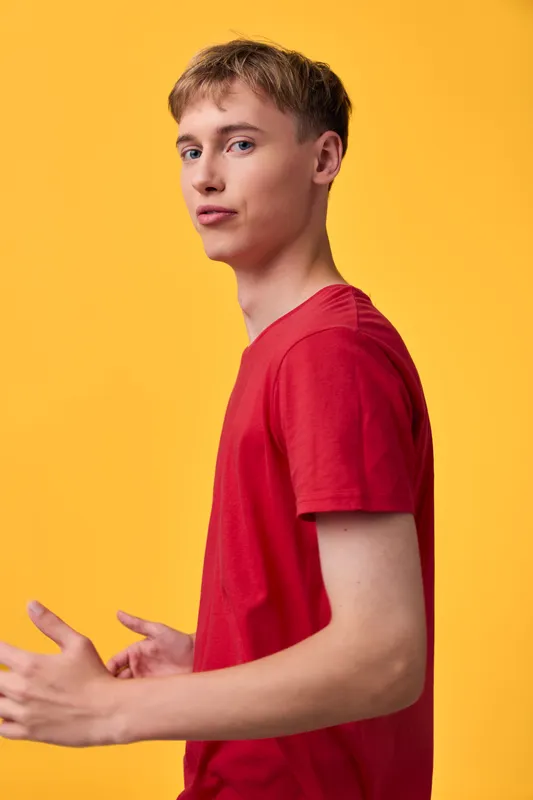 Young man, red shirt, casual studio scene with a bright yellow background, forward gaze and relaxed pose, clean lighting, modern fashion vibe, minimal and bold