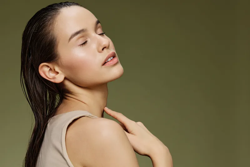 Portrait of a serene young woman with long hair against a soft green background, embodying natural beauty and calmness, perfect for wellness and skincare themes
