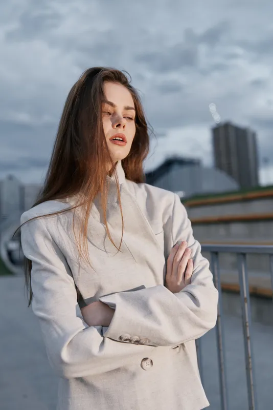 Confident business woman in elegant attire posing against a modern urban backdrop, conveying strength and ambition in a professional setting.