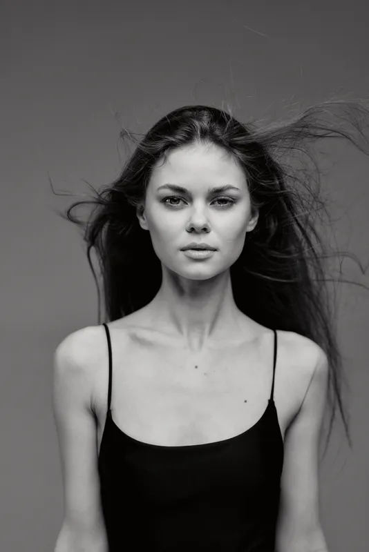 Black and white portrait of a young woman with flowing hair wearing a black tank top