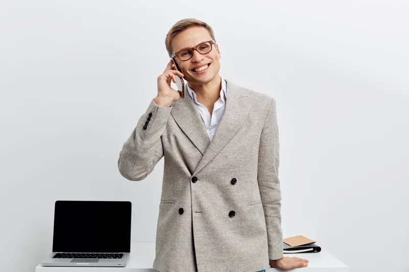 smiling man talking phone digital nomad smart casual wear glasses with laptop on white background remote work concept