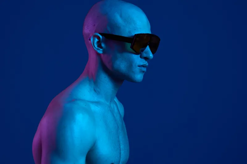 Dynamic man in sunglasses, showcasing a vibrant blue and purple color scheme, embodying a modern and edgy style. Perfect for fashion and lifestyle themes.