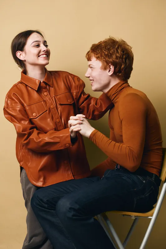 Young people, couple and happiness with smile embracing in studio. Man and woman wearing casual clothes share joyful moment with affection and friendship on beige background.
